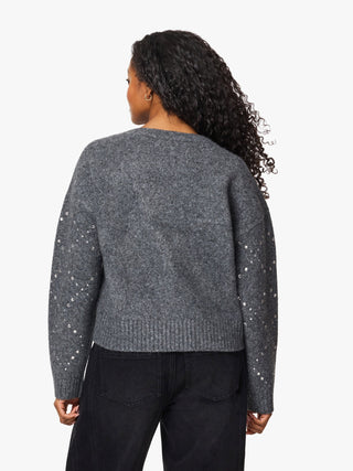 A woman shown from the back wearing a dark gray knit sweater with silver beaded details on the sleeves, paired with black pants, against a plain white background.