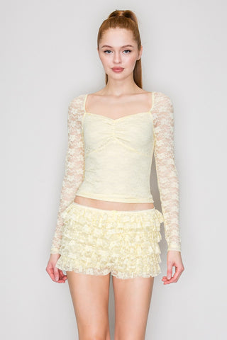 Woman wearing a light yellow lace top featuring womens clothing from Iris.