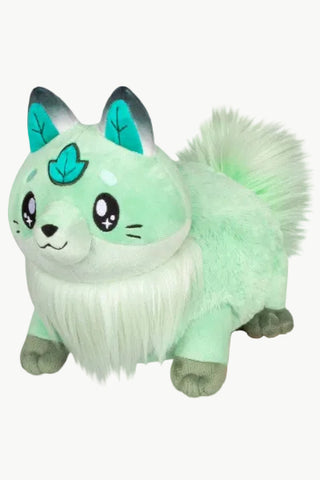 A plush toy shaped like a cute mint-green fox or cat with fluffy white fur, held by a person's hand against a plain white background.