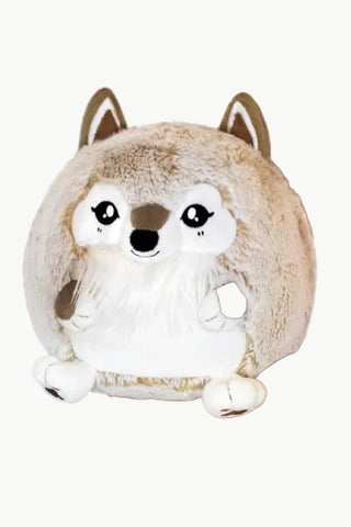 A round, plush, wolf-like stuffed animal with fluffy tan and white fur, held in two human hands against a plain white background.