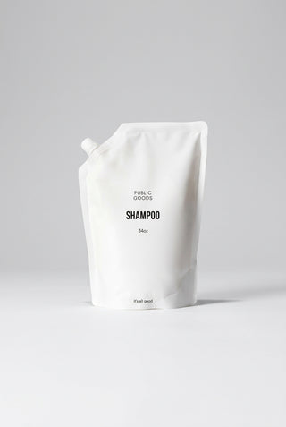 A white pouch labeled 'PUBLIC GOODS SHAMPOO 34oz' made from recycled post-consumer plastics.